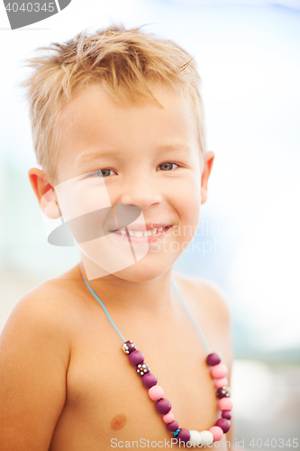 Image of Young Blond Boy Wearing Beaded Necklace on Beach