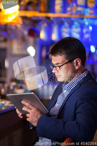 Image of Businessman reading a tablet in a cocktail bar