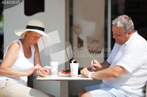 Image of Couple sitting in cafe while using gadgets