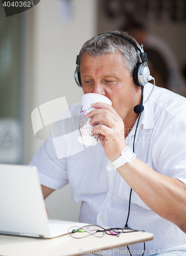 Image of Man Drinking Coffee and Using Laptop at Cafe