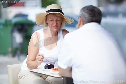 Image of Elderly couple eating in outdoor cafe