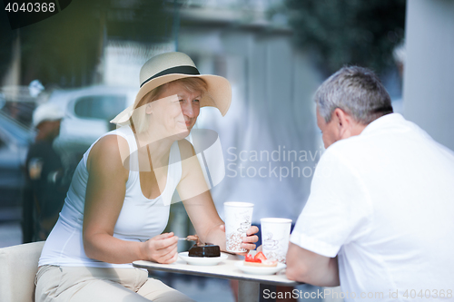 Image of Smiling elderly woman eating in cafe with her husband