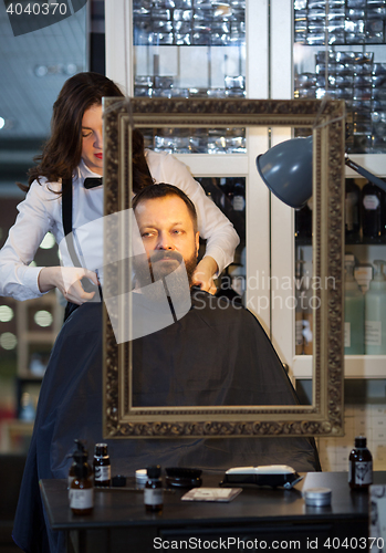 Image of Man having his beard and hair trimmed at a barber