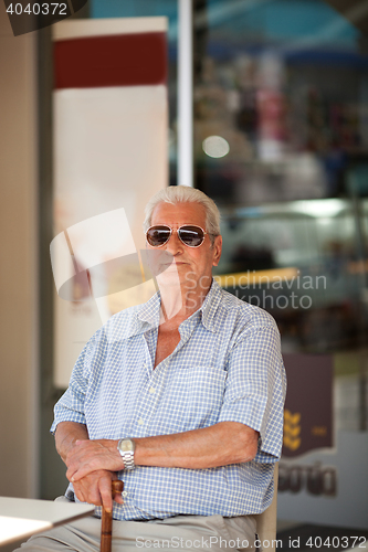 Image of Elderly man waiting at a table outside a store