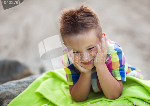 Image of Boy with Head in Hands on Green Beach Blanket