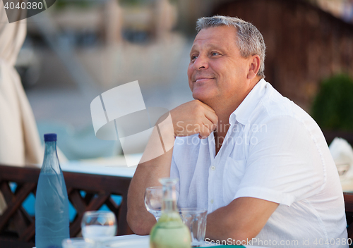 Image of Smiling pensive middle-aged man at a restaurant