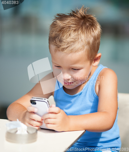 Image of Portrait of blond kid using cell phone