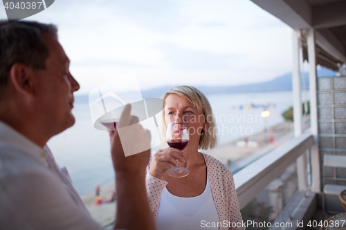 Image of Couple Drinking Red Wine on Balcony of Beach Hotel