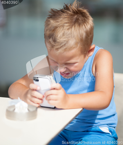 Image of Young boy peering closely at a mobile phone