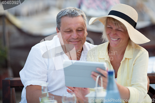 Image of Smiling middle-aged couple using a tablet