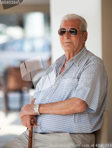 Image of Senior man in sunglasses sitting waiting