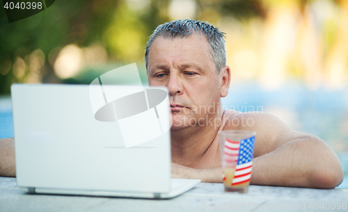 Image of Man in Swimming Pool with Laptop and Beverage