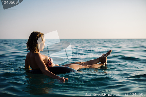 Image of Back view of relaxing woman floating on inflatable ring