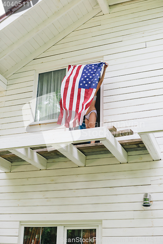 Image of Unrecognizable girl in underwear holding spreaded american flag