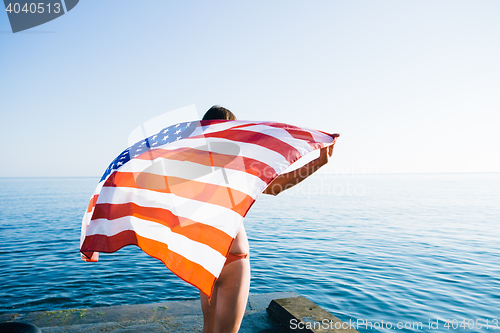 Image of Back view of female with American flag against  sea