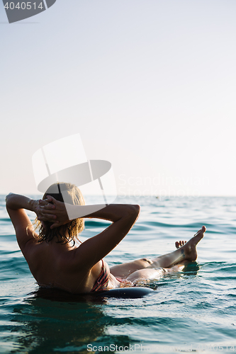 Image of Back view of relaxing woman floating on inflatable ring