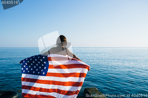 Image of Back view of female with American flag against  sea