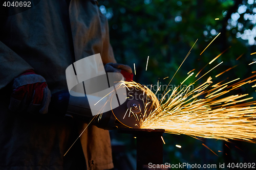 Image of Worker cutting metal with grinder. Sparks while grinding iron