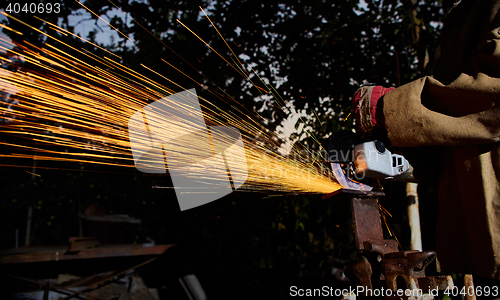 Image of Worker cutting metal with grinder. Sparks while grinding iron