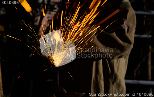 Image of Worker cutting metal with grinder. Sparks while grinding iron