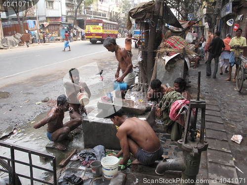 Image of Streets of Kolkata. Indian people wash themselves on a street