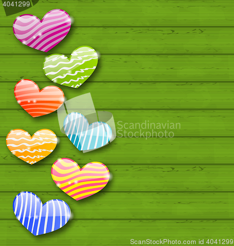 Image of Multicolored striped hearts on green wooden texture for Valentin