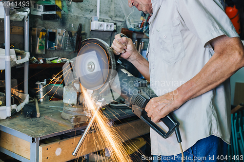 Image of Senior man working with angle grinder