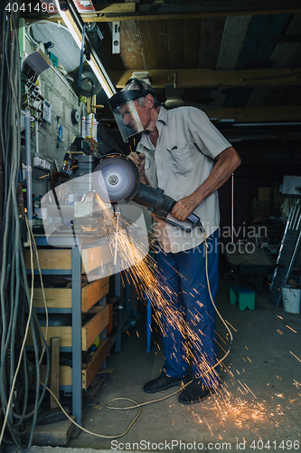 Image of Senior man working with angle grinder