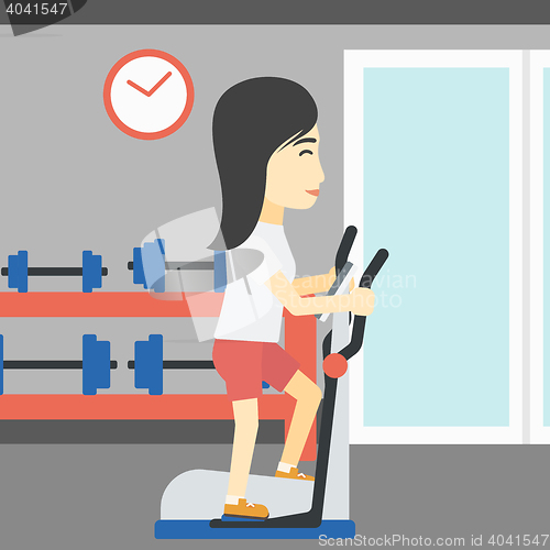 Image of Woman exercising on elliptical trainer.