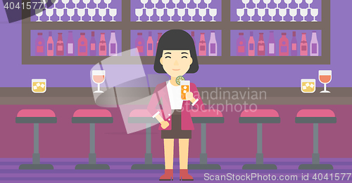 Image of Woman drinking orange cocktail at the bar.