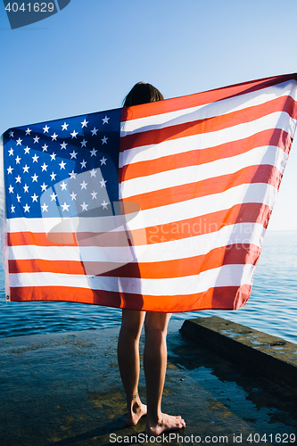 Image of Back view of female with American flag against  sea