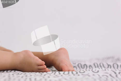 Image of Barefoot baby on bedspread