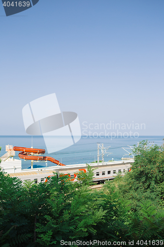 Image of Train railing along coastline with aquatic slide against the sea