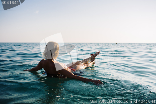 Image of Back view of relaxing woman floating on inflatable ring