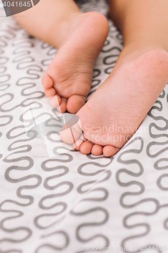 Image of Barefoot baby on bedspread