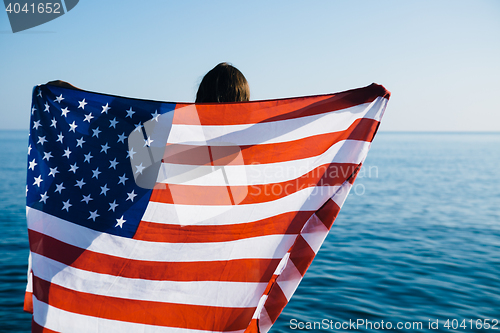 Image of Back view of female with American flag against  sea