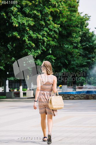 Image of Young brunette woman walking in park against of fountain