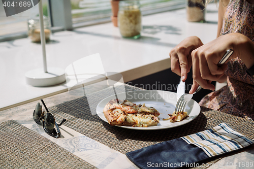 Image of Unrecognizable woman eating pizza in cafe