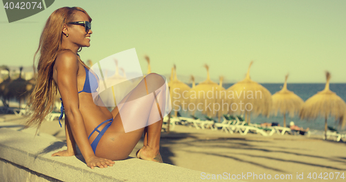 Image of Happy African Girl in Bikini Sits at Beach Bench