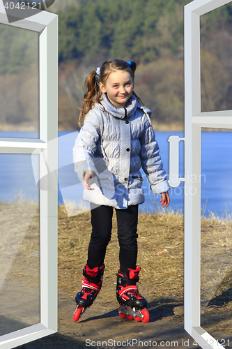 Image of girl goes in roller skates seen from the window