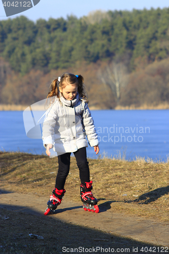 Image of young girl goes in roller skates on the ground