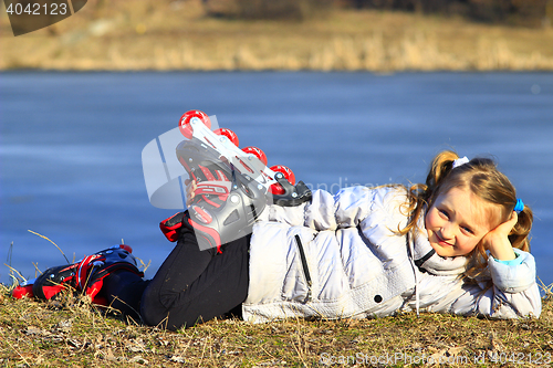 Image of young girl in roller skates lays on the ground