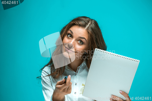 Image of Surprised young business woman with pen and tablet for notes on blue background