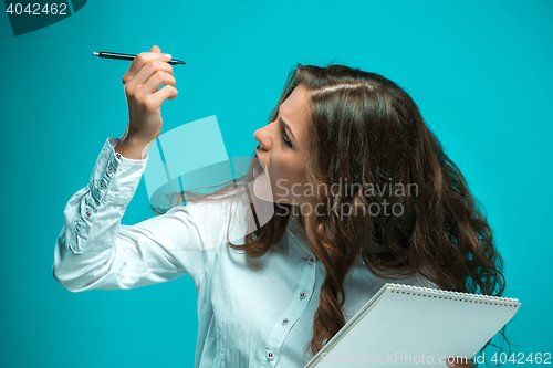 Image of Surprised young business woman with pen and tablet for notes on blue background