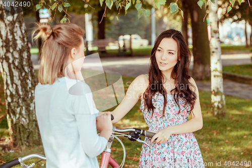 Image of The two young girls with bicycles in park