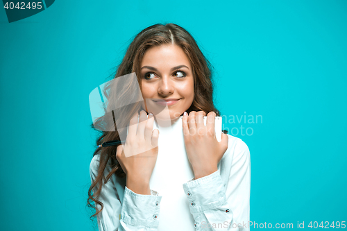 Image of The smiling young business woman with pen and tablet for notes on blue background