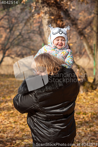 Image of The little baby girl and grandmother standing in autumn leaves