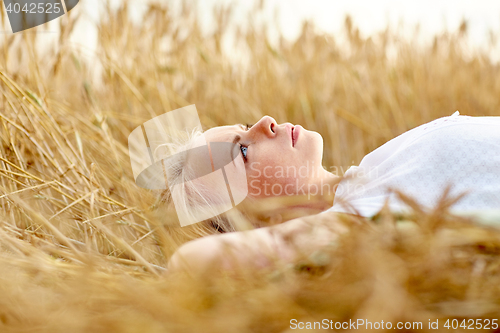 Image of young woman lying on cereal field and dreaming