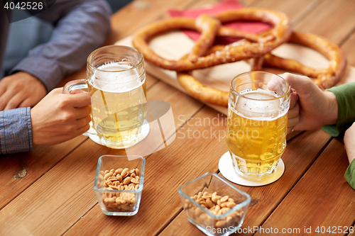 Image of close up of hands with beer mugs at bar or pub