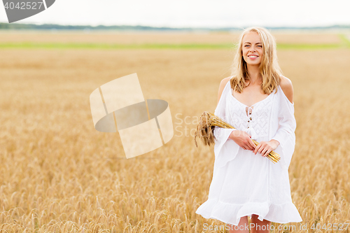 Image of happy young woman with spikelets on cereal field